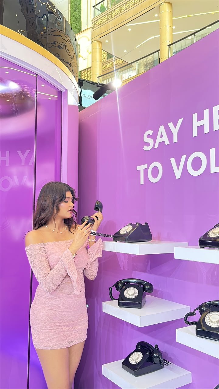 Vaishnavi Kadekar in a pink lace dress at a purple brand installation with vintage telephones